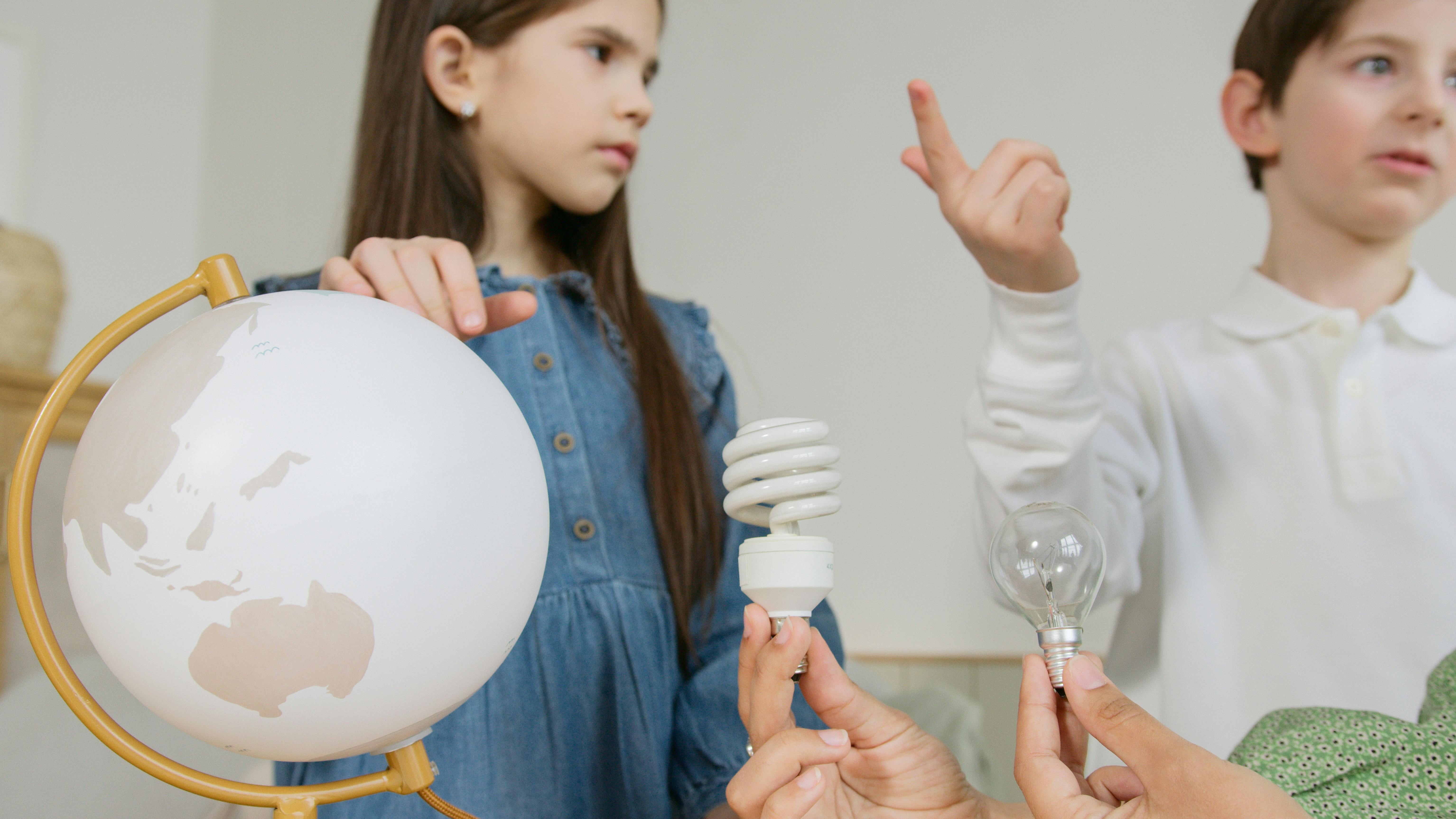 Children with globe and energy efficient lightbulb