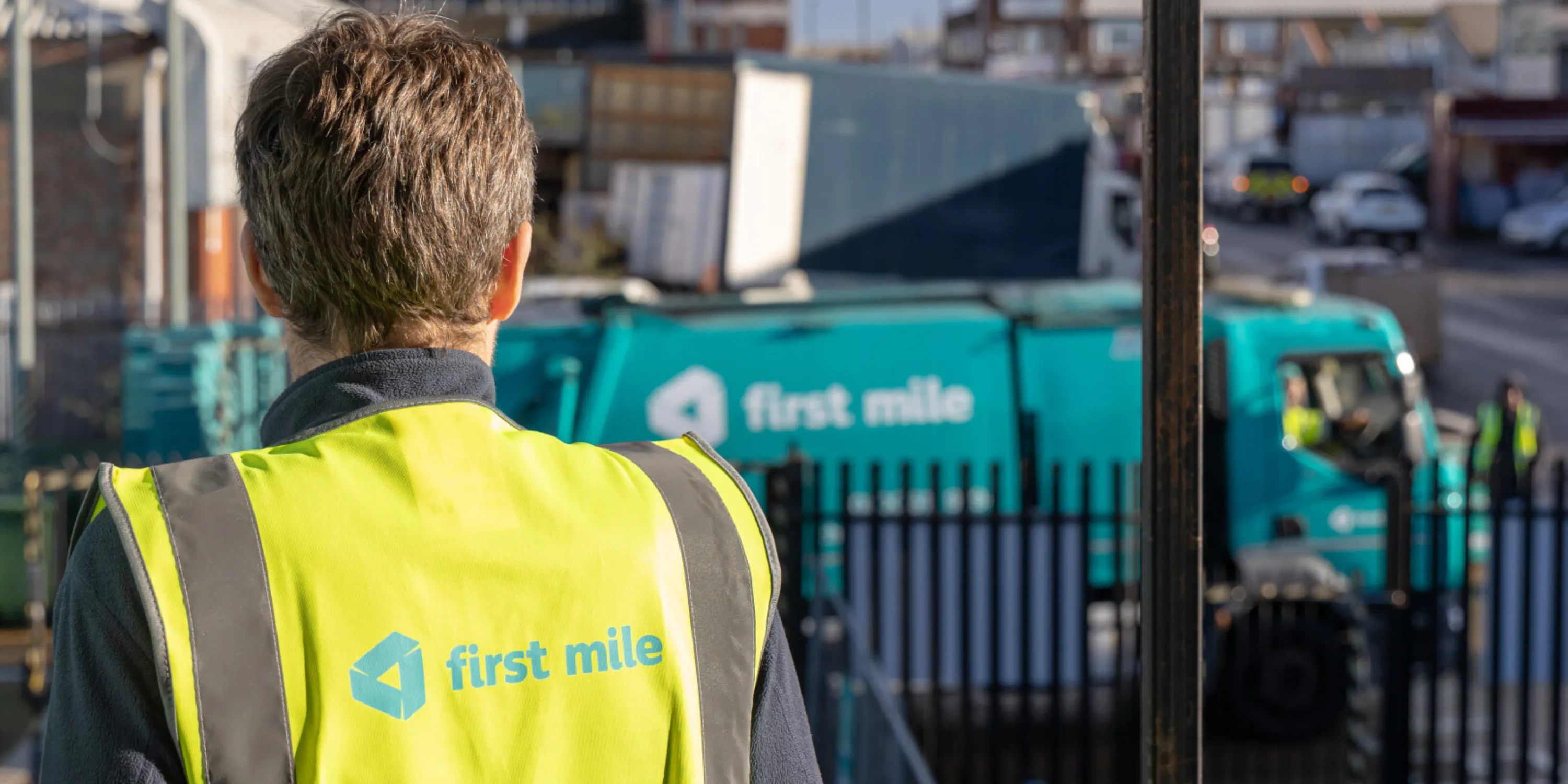 First Mile worker with a compactor van in the distance